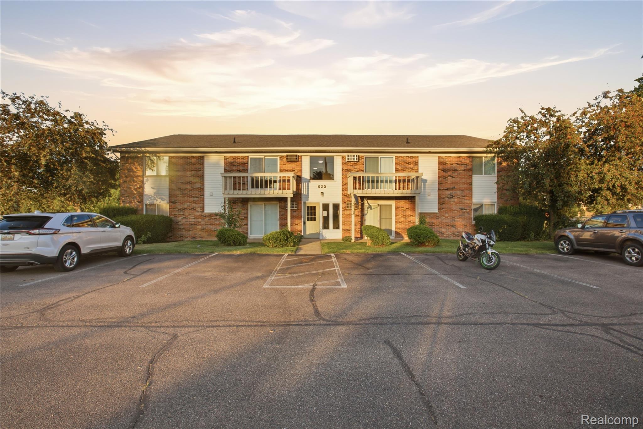 Brick apartment building featuring multiple balconies and a dedicated parking lot