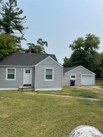 Exterior featuring light gray siding, a dark shingle roof, white trim windows, and a detached two-car garage with a white overhead door