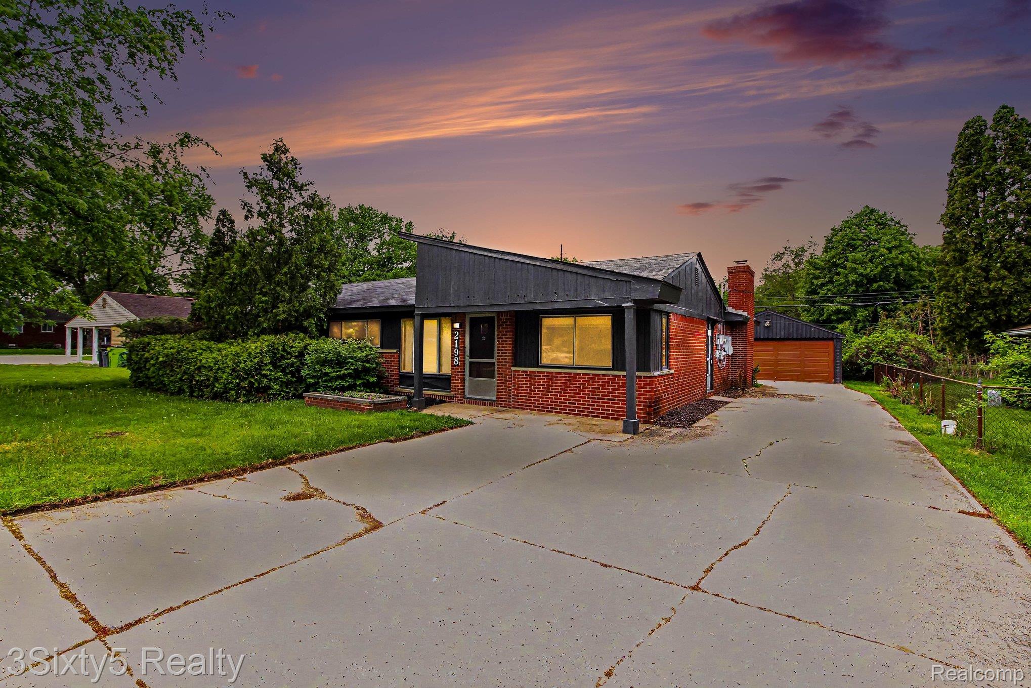 View of front of property with brick siding, a garage, a chimney, and an outbuilding