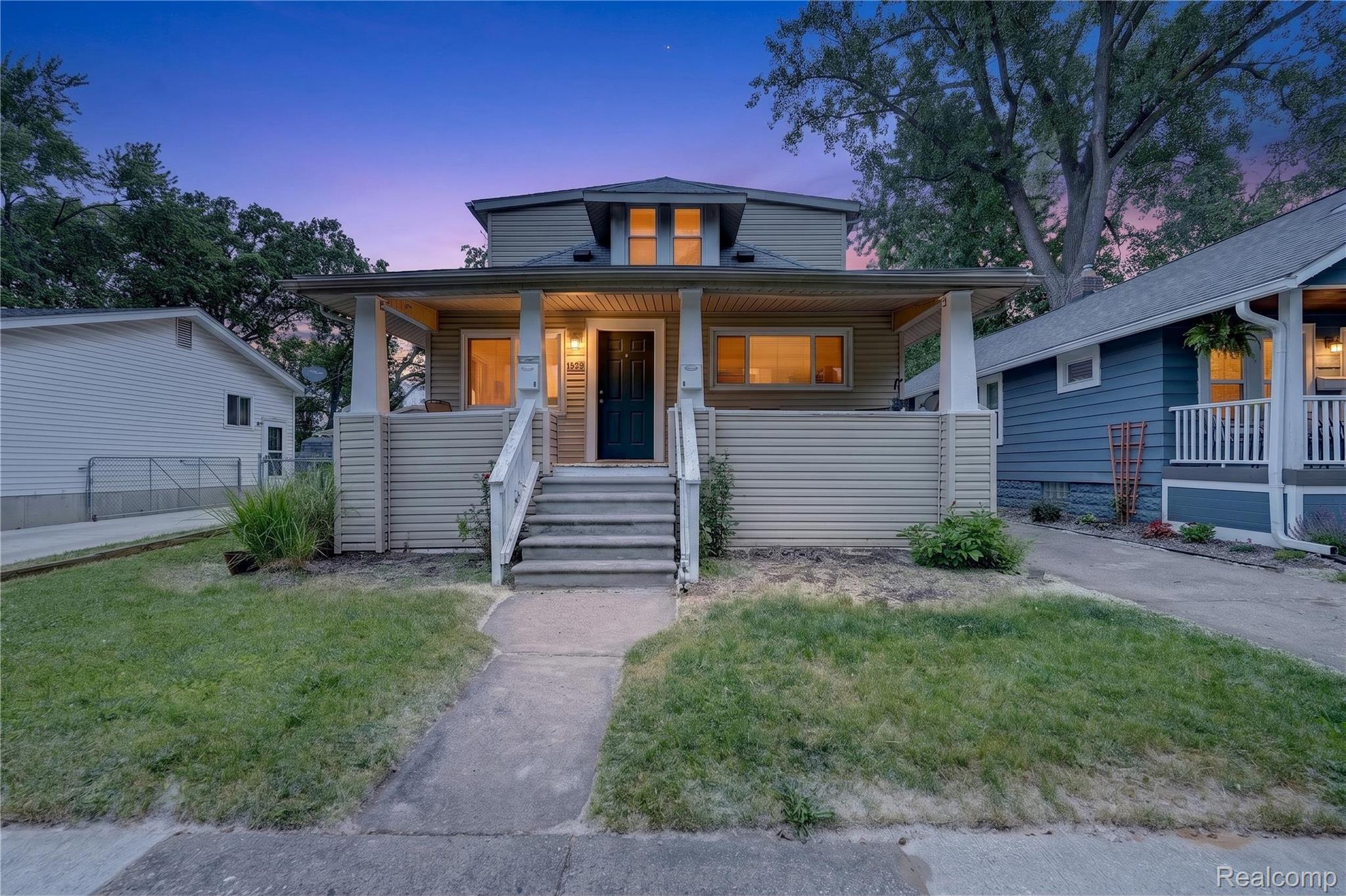 Inviting front facade featuring a covered porch, white column supports, and a dark entry door