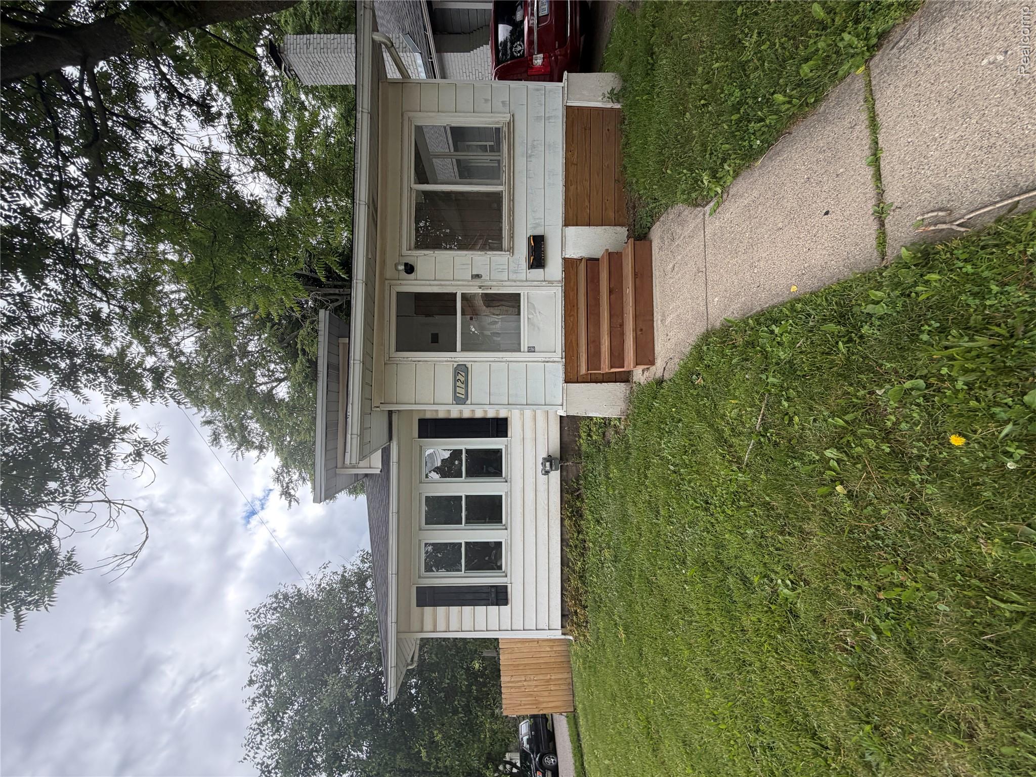White siding exterior with black window shutters and a light-colored entry door
