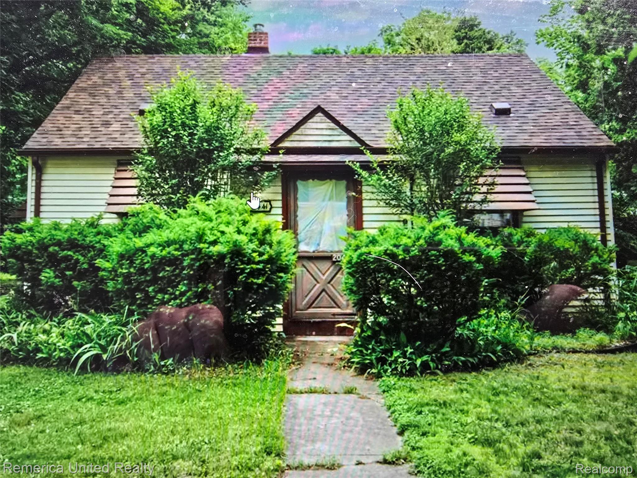 View of front of house featuring a chimney, a shingled roof, and a front lawn