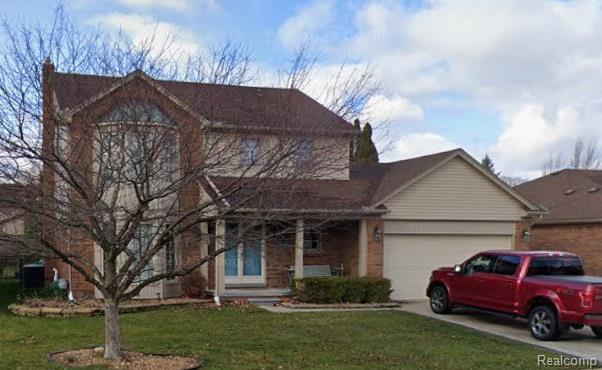 View of front facade featuring a porch, a front yard, a garage, brick siding, and concrete driveway