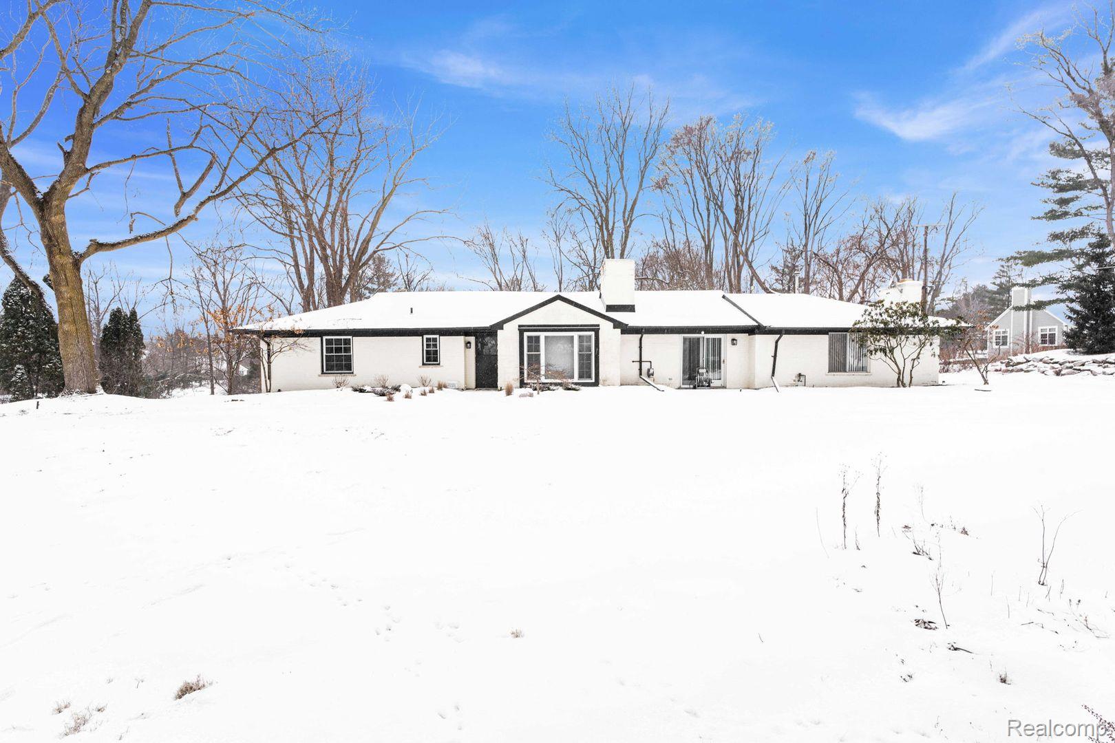 Snow covered back of property featuring a chimney