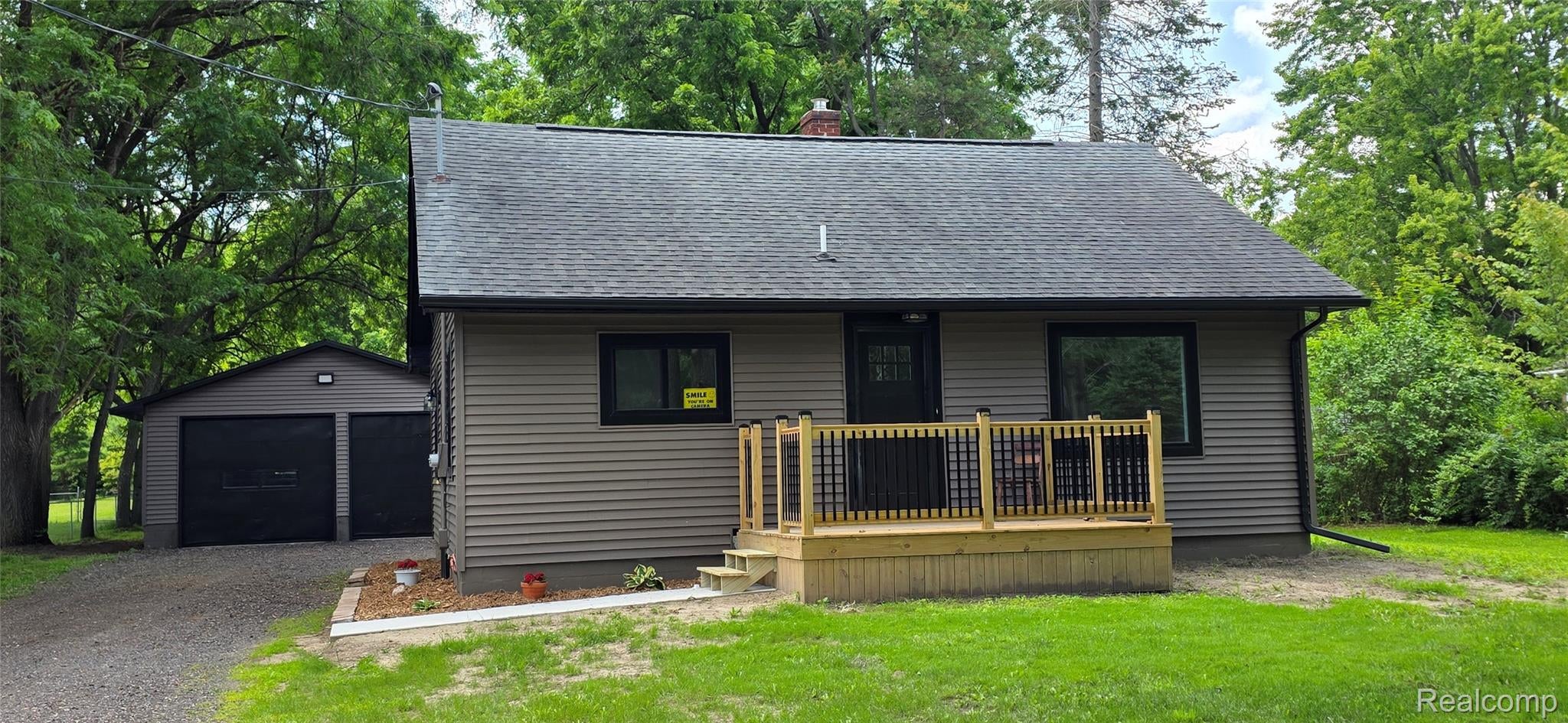 Beige horizontal siding exterior with a dark shingle roof and black trim windows
