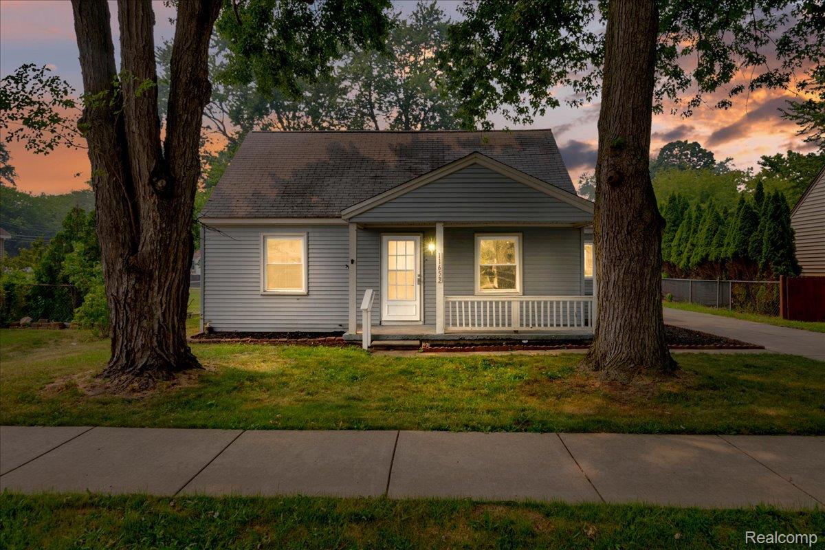 Ranch-style residence featuring horizontal siding, a covered front porch with white railings, and a prominent front door with side panel windows