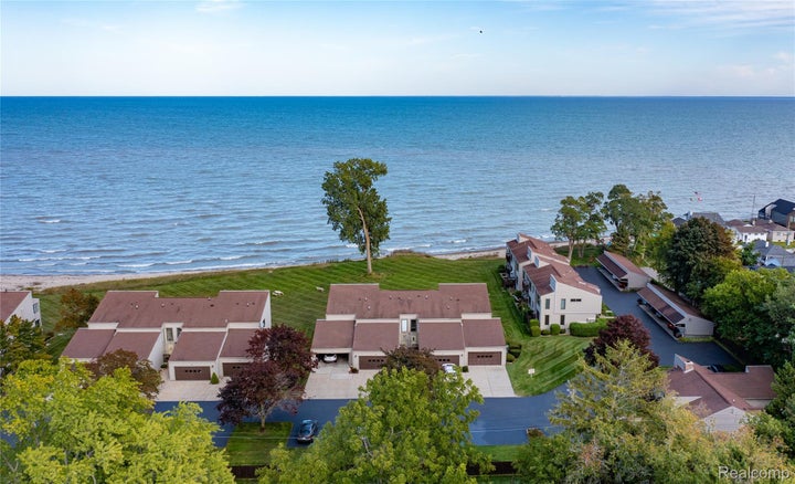 Coastal property featuring a sand beach, expansive water frontage, and mature trees