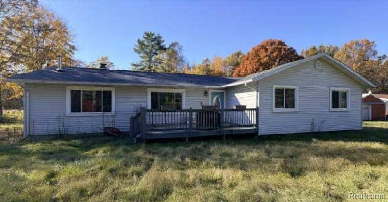 Back of property featuring a deck and a lawn