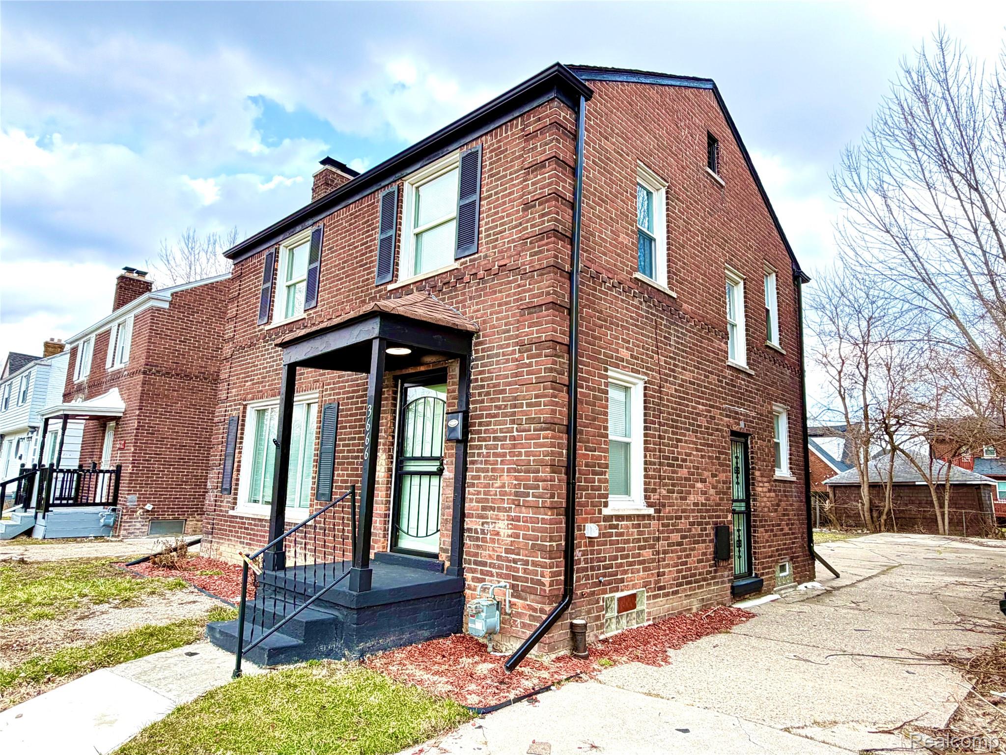 View of front of home with brick siding and a chimney