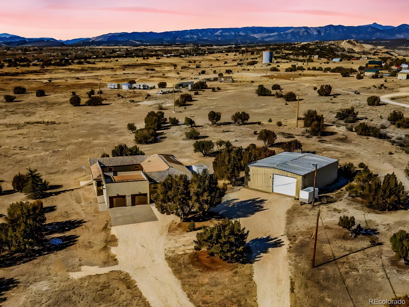 Front Elevation with Mountain View ? Front-facing aerial image of the home and rooftop patio, with unobstructed views of open land and distant peaks.