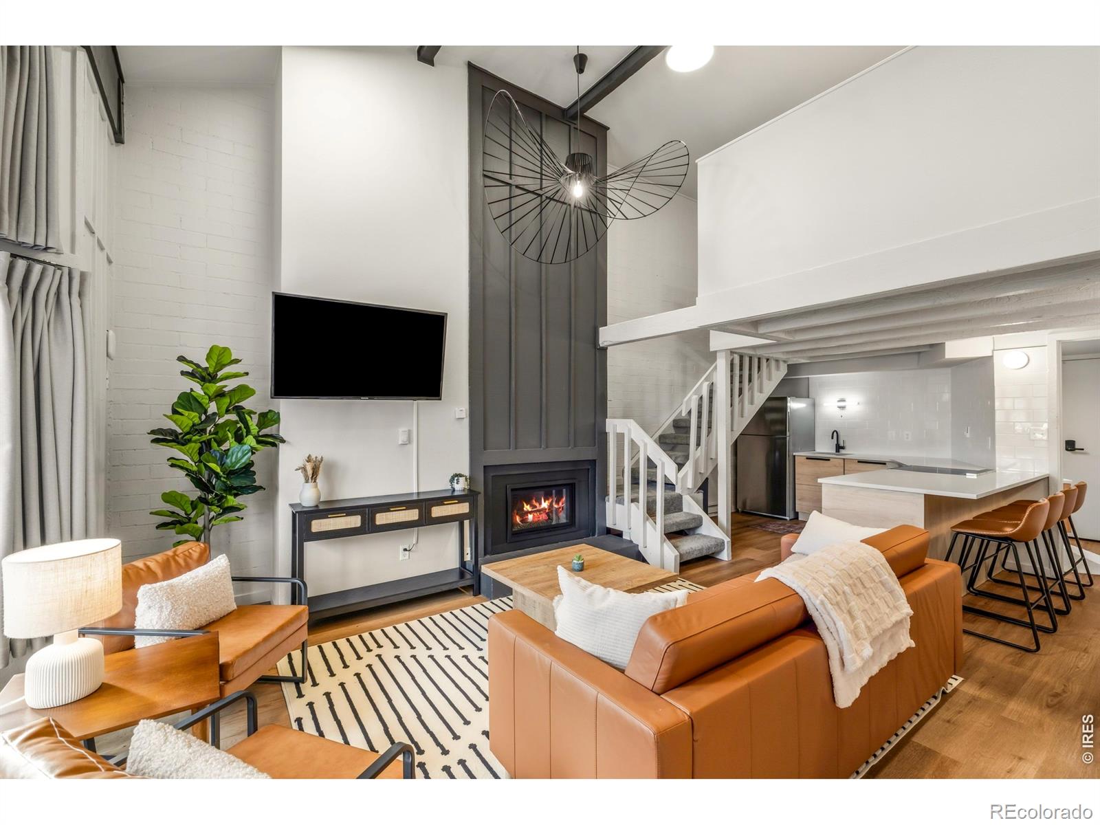 Gather around the fireplace in a light-filled living space that seamlessly blends bold design, soaring ceilings, and premium finishes at every turn.