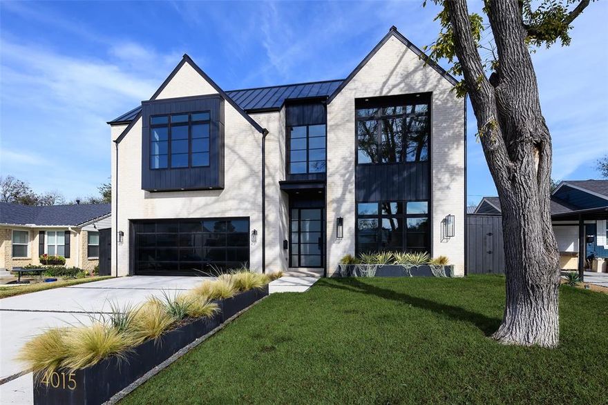 A warm modern showpiece by award-winning, third-generation Chris Sandlin Homes, this 4,750-SF residence blends striking architecture with effortless livability. Light brick, black metal rooflines and expansive black-framed windows lead to interiors finished with solid oak flooring, smooth gallery walls and bespoke rift-sawn white oak cabinetry. The open great room soars to 12 feet, anchored by an architectural staircase and a sleek 48in Montigo linear fireplace, seamlessly connected to the dining area and a chef’s kitchen outfitted with Monogram appliances, a quartz-wrapped waterfall island with integrated lighting, full-height slab backsplash and hood, a wet bar with wine storage and a hidden walk-in pantry. A quiet front study offers built-ins and natural light. The main-level primary suite is a serene retreat highlighted by a white-oak ceiling beam and a spa bath with a freestanding soaking tub beneath a statement chandelier, a large walk-in shower with floating bench and custom dual vanities; the expansive custom closet links directly to the first-floor laundry for everyday ease. Upstairs, a generous game room with serving bar anchors four private en-suite bedrooms and a second laundry. All-season outdoor living shines with a covered patio, gas fireplace, full kitchen and motorized screens overlooking a level, fenced yard. Beyond the aesthetics, the home delivers serious performance: an over-engineered foundation, premium insulation, durable metal roofing, tankless water heaters and a comprehensive security system. Thoughtful design, elevated finishes and superior construction—contemporary luxury, perfected.