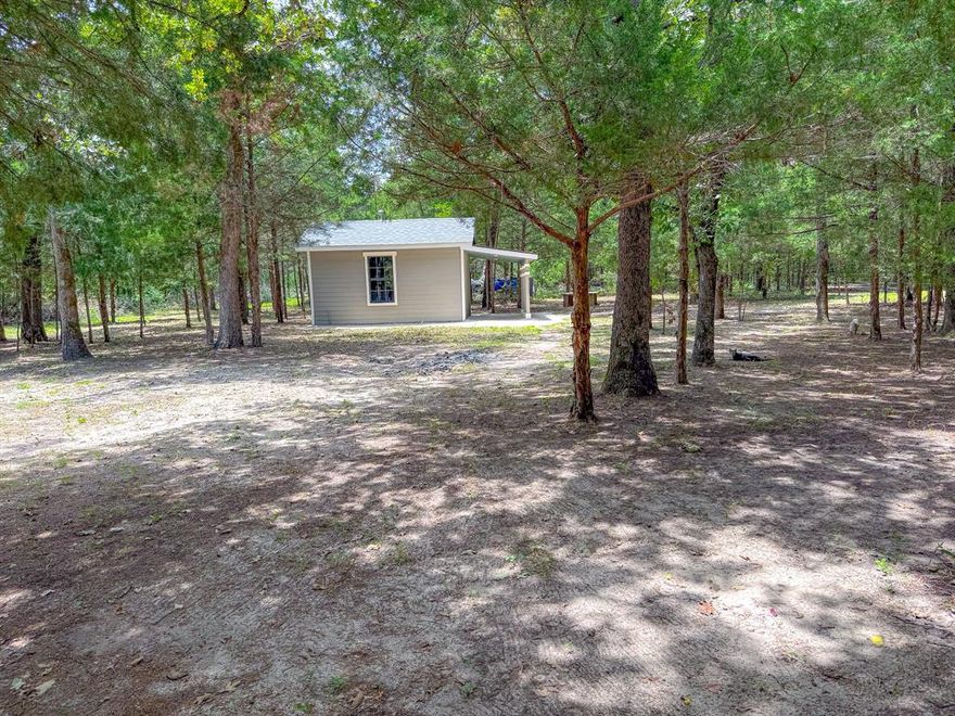 Country charm meets versatile living on 2 acres, Welcome to your slice of Texas freedom. Just minutes from 145 and outside city limits! This 3 bedroom, 2 bathroom home sits on two beautiful acres, half cleared, half lightly wooded - offering privacy, space, and room to grow. The layout features a spacious primary suite with an attached bonus room that can serve as a home office, nursery, or creative flex space. From this room, step out to a covered porch area -perfect for quiet mornings or relaxing evenings. Behind the main home you'll find a detached in law suite featuring an open layout, bathroom, and closet. Electrical and plumbing are already in place, offering excellent potential for a guest space, rental, or studio.  The property also includes a detached outdoor kitchenette a versatile outbuilding with a window, covered sink area, and plenty of space for a refrigerator, deep freezer, or additional storage. Great for canning, hosting gatherings, or simply keeping extra appliances out of the main home. This property offers the ideal blend of peace and practicality plenty of trees for privacy, open space to build or garden, and the flexibility of being outside city limits. Whether you're looking for a quiet homestead, multi generational setup, or an income producing opportunity, this property is ready to meet your vision.