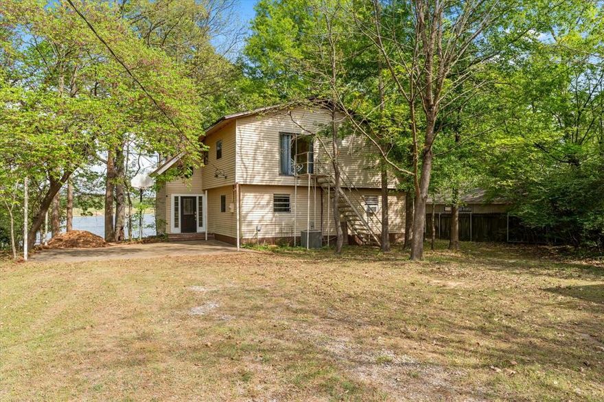 Welcome to 405 Triple South Dr, a rare lakefront retreat on beautiful Lake Cypress Springs. Situated on just over an acre with private shoreline, this property offers the perfect blend of relaxation, recreation, and space to gather.

Wake up to stunning sunrises over the water and enjoy peaceful mornings from the expansive deck overlooking a wide, tranquil bay. With no homes directly across the water, the view feels private and untouched—ideal for those seeking a true escape.

The home features 6 spacious bedrooms and 2 full bathrooms, providing plenty of room for family and guests. The open-concept living, kitchen, and dining areas create a comfortable flow for entertaining, while large windows bring in natural light and showcase the lake views.

Step outside to enjoy everything this property has to offer, including a large open deck, outdoor kitchen, and a two-stall boathouse with an expansive dock—perfect for boating, fishing, and lakeside entertaining. Whether you're hosting summer gatherings or enjoying a quiet weekend getaway, this home is built for making memories.

Located in a calm, protected cove with excellent water access, this property is ideal as a full-time residence, vacation home, or investment opportunity. Experience the best of East Texas lake living at 405 Triple South Dr on Lake Cypress Springs.