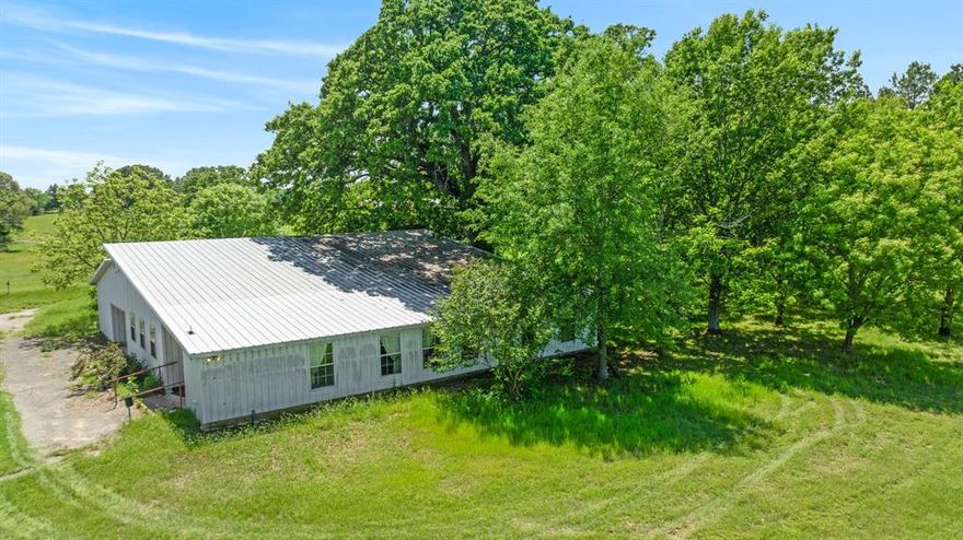 Travel out to the country and imagine yourself on this 53.65 acre ranch in NW Lamar county, near the Fannin county line. Scatterd trees, a few woods and wide open spaces, this is something that can make everyone happy. This property offers an owner a multitude of opportunities with the 53+acres, house, outbuildings and country location.  The land has a slight roll with a creek running through it making it an ideal piece of paradise for a buyer.  Fenced and cross-fenced, the property is set up for cattle, horses, hay production or recreational use. With the barn, storage building and workshop, you have everything you need to make this an active ranch or county paradise.  The barndominium styled residential structure offers over 3500 square feet of living space including an open floor plane providing ample space for family and friends.  The kitchen is open to the living area with plenty of cabinets for storage.  The primary bedroom is spacious withe private full bath and walk-in closet.  Another and possibly a 3rd bedroom with bath completes the sleeping quarters.  The oversized enclosed patio is perfect for evening or morning views of the land.