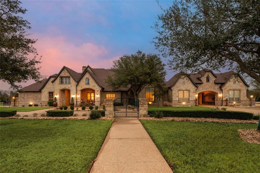 Located in Kingsbridge, one of the most desirable and prestigious neighborhoods in Rockwall, this warm and sophisticated 1 story is sure to offer space for the whole family.  This luxurious property offers expansive custom wood work which includes lawyers paneling in the study numerous built-ins hardwood flooring throughout, stained millwork and exposed beams on ceilings in gathering areas.  The cooks kitchen with granite counter tops and stainless appliances includes gas cooktop, prep island with vegetable sink, lots of custom storage spaces, and Butlers Pantry.  The primary suite with tray ceiling offers a sitting area and luxury bath with custom closet.  The open gameroom with wet bar leads to the large theatre room with screen and projector.  The family room and breakfast room with walls of windows that overlook the huge outdoor living areas including built-in grill and sitting area with fireplace which extends to the gorgeouos backyard with beautiful pool and spa with waterfalls, firebowls, a pergola, lots of custom outdoor landscape lighting and stone firepit sitting area.  The 2Br, 2 Bath custom guest house with garage has a full kitchen, primary suite, guest room, a laundry room and a large sitting porch that overlooks the backyard and pool area.  There is plenty of parking for guests and space for the hobbyist with a circle drive and a porte cochere leading to the motorcourt and garages.