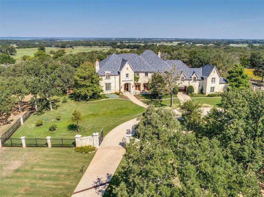 Discover exceptional luxury living in this magnificent custom-built estate featuring an impressive 9,100 square foot home spanning across 27.038 acres. This architectural masterpiece showcases state-of-the-art construction with premium materials and thoughtful design throughout. Enter through dual security gates leading to a concrete driveway that sets the tone for the grandeur within. Rich maple wood millwork flows seamlessly throughout the home, complemented by an elegant travertine marble staircase with custom iron work that serves as a stunning focal point. The formal dining room features French doors and dual chandeliers, creating an atmosphere perfect for memorable gatherings. The sophisticated study boasts a coffered ceiling, fireplace, alabaster lighting, and cleverly concealed hidden closets behind the walls. The extraordinary primary suite includes a sitting room, reading room, luxurious steam shower, and a custom closet.  Stunning great room opens to a kitchen any culinary enthusiast will appreciate. This gourmet kitchen is equipped with commercial-grade double ovens, gas range, and Sub-Zero refrigerator and freezer. The home's superior construction includes foam insulation and solid-core doors throughout.  Entertainment options abound with a media room, a game room featuring a mahogany bar, and a dedicated card table room. Step outside to enjoy the motorized screened in patio with built-in gas grill and fireplace or relax on the expansive patio off the game room with its elevated balcony overlooking the backyard.  Wine connoisseurs will be delighted by the temperature-controlled wine room accommodating 2,300 bottles. Additional luxuries include three walk-in attics, a laundry room with dog shower, and guest quarters with separate entrance.  Every bedroom includes ensuite bathrooms and walk-in closets, ensuring comfort and privacy for all occupants. Substantial 60 x 40 three stall horse barn with workshop featuring electrical service.