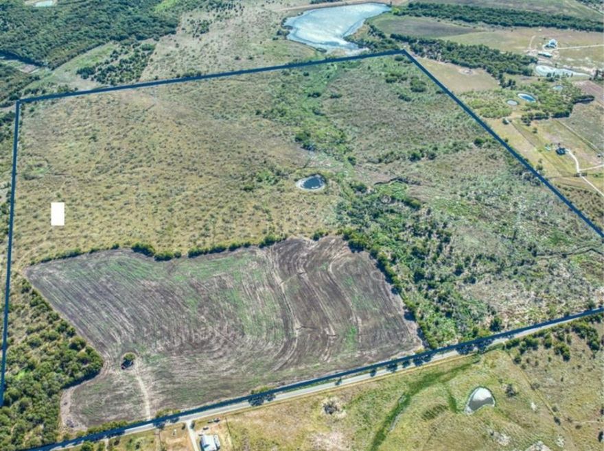 This 169-acre property offers a versatile and scenic landscape, featuring a nice tank (estimated size 1.5 acres) and a creek that runs through the land (floodplain along its course). There's also a large lake on an adjoining parcel at the back of the property that, when full, covers about 2 acres on this parcel. Plenty of trees are scattered throughout, creating a peaceful, natural setting. The property boasts over 2,200 feet of road frontage, providing excellent accessibility. Approximately 30 acres are currently leased and cultivated for hay, and the property benefits from an agricultural exemption. Roughly 75 acres of the land are located within the city limits of Ennis, making it an attractive option for future development. It is also situated within an opportunity zone, which could provide financial incentives for various projects. The property was once in the path of a now-defunct high-speed railroad. Additionally, a 20' water easement runs along the property at the road, providing convenient access to water through the Rocket Special Utility District. Survey shows two water meters near the barn. With its combination of agricultural, natural, and developmental features, this property presents a variety of possibilities. Schedule your tour today!