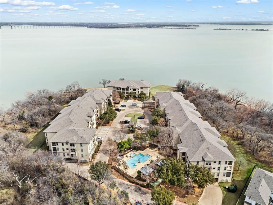 Enjoy lakefront living at its finest in this beautiful 3-bedroom, 2-bath condominium at Water’s Edge on Lewisville Lake. Light and bright throughout, this inviting home features an open-concept layout with wood flooring in the living, dining, and kitchen areas, and granite countertops in the kitchen—perfect for both everyday living and entertaining. Step out onto your private balcony and take in peaceful lake views, complete with automatic shades for added comfort and convenience. Additional automatic shades inside the home provide both privacy and ease of use. The spacious primary suite and well-appointed secondary bedrooms offer comfort and flexibility for guests, family, or a home office. Recent updates include a new AC system installed in 2025, offering peace of mind for years to come. Convenience is key with two prime covered parking spaces located near the elevator. Residents enjoy resort-style amenities including a community clubhouse, pool and spa, and fitness center. Ideally situated with easy access to Denton, Grapevine, Dallas, and Frisco, and just a short drive to DFW Airport, this home offers the perfect blend of relaxation and accessibility. Don’t miss your chance to experience lakeside living at Water’s Edge!