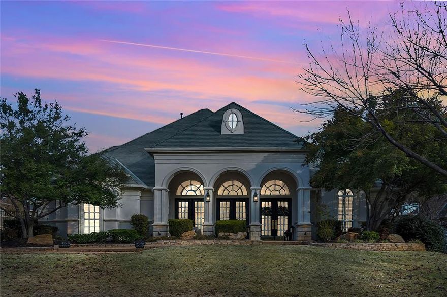 Striking European-inspired architecture and refined modern updates define this exceptional Southlake residence, ideally located in sought-after Carroll ISD. A dramatic arched loggia and stucco exterior create a grand first impression, complemented by mature landscaping and a gated driveway.
Inside, the home showcases soaring ceilings, wide-plank hardwood floors, and a light-filled open layout designed for both everyday living and elegant entertaining. The stunning two-story living room features expansive arched windows, flooding the space with natural light and seamlessly connecting indoor and outdoor living. A dramatic staircase and balcony overlook add architectural interest and timeless appeal.
The private study is beautifully appointed with custom built-ins and French doors, offering an ideal work-from-home space. The formal dining room is framed by custom wall detailing and designer lighting, providing an inviting setting for gatherings and special occasions.
Thoughtful design, elevated finishes, and a neutral modern palette carry throughout the home, creating a sophisticated yet welcoming atmosphere. The gated motor court and side-entry garage enhance both privacy and curb appeal.
Conveniently located near premier shopping, dining, and parks, this home offers a rare combination of architectural character, updated style, and an unbeatable Southlake location.