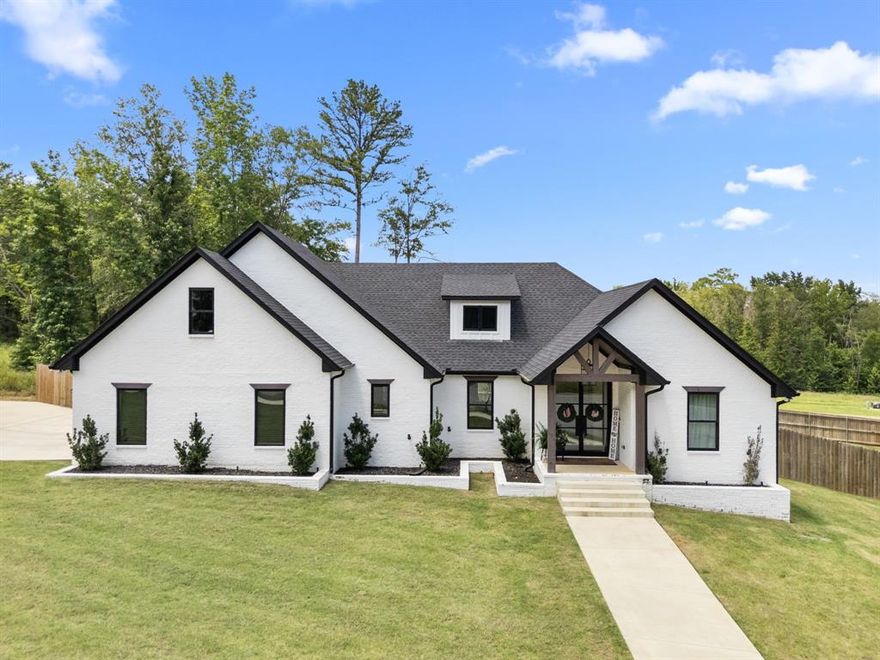 Don't miss your opportunity to own this beautifully crafted 4-bedroom, 3-bath custom home in the gated Caddo Ridge Estates of Tyler. Built in 2024 on a spacious cul-de-sac lot, this modern retreat offers over 2,500 sq ft of open living space designed with style and comfort in mind. Soaring vaulted ceilings, a dramatic floor-to-ceiling fireplace, and abundant natural light make the main living area both striking and inviting. The kitchen is a true centerpiece with a large island, stainless steel appliances, double ovens (including air fryer), and a generous walk-in pantry—perfect for everyday cooking or entertaining. The primary suite features a spa-like bath with a soaking tub, walk-in shower, and dual vanities for a touch of luxury. Thoughtful details continue throughout, including a built-in dog wash station in the laundry room. Step outside to enjoy a covered back patio and a sparkling in-ground pool that’s ready for summer fun. Located within Whitehouse ISD and offering easy access to Hwy 69 and Toll 49, this home delivers the perfect blend of luxury, function, and convenience. Schedule your showing today!