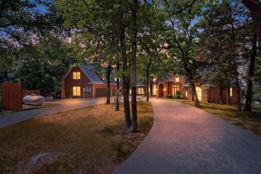Welcome to this stunning Lake Lewisville Lakefront Estate, where sweeping water views add to this unique property. Main house is recently updated with new flooring and fixtures, plus bathroom & kitchen updates. Invite guests into grand living area, accented by dramatic staircase, stone fireplace, and incredible water views looking out to the horizon. Stately study is accented by sleek hardwoods, new carpet, and boasts impressive rounded windows, generous built-ins and secret door to storm shelter! Dining room glows under shimmering chandelier, making an elegant space for entertaining. Unique hardwood ceiling accents gourmet kitchen and provides ample countertop and built-in storage space. Luxury touches, including built-in industrial fridge, island, prep sink, and Viking hood make cooking a delight. Connected breakfast nook continues the thoughtful hardwood detailing and provides close patio access and generous views of expansive lake. Oversized primary is a retreat, with rounded bay windows looking out to the lake with ample space for peaceful sitting area. Spa-like primary bath includes dual vanities, separate garden tub and shower, and 2 WIC that provide plenty of custom built-in storage. Additional downstairs bedroom is perfect guest suite, with ensuite bath and WIC. Downstairs bright sunroom features built-ins, making it ideal for craft room or additional office space.

Upstairs offers roomy game room with bay windows and convenient wet bar for entertaining. Additional bedrooms include jack & jill bath and WIC. 2nd floor of garage includes additional apartment space, with kitchen, full bath, living area, and bedroom. Outdoor oasis features generous multi-level patio space, perfect for outdoor seating or dining. Backyard leads down to the water with stone pathways and includes private woods for quiet seclusion. Additional features include oversized garage, 3 water heaters, 5 heat pumps, geothermal system for HVAC, and propane generator!