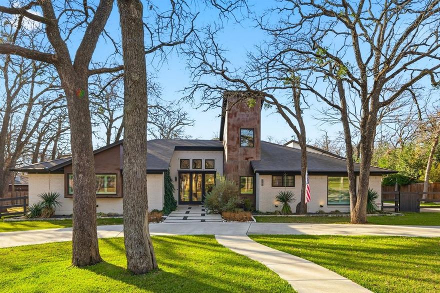 Set on an expansive .6-acre lot framed by mature oak trees, this fully renovated modern residence offers a rare sense of privacy, presence, and luxury just minutes from the heart of Colleyville. A circular driveway creates a grand front approach, enhancing curb appeal while providing abundant parking for guests. Originally built in 1972 and completely reimagined and expanded in 2018, the home spans 3,220 square feet with 4 bedrooms, 4 full baths, a dedicated media room, and a power generator, delivering comfort, flexibility, and peace of mind. The light-filled interior showcases designer finishes throughout, including a stunning chef’s kitchen equipped with a convection oven & induction cooktop with restaurant-grade vent fan, wine cooler, quartz countertops, spa-inspired bathrooms, updated flooring, upgraded roof, HVAC, & integrated smart home tech. A spacious media room offers the perfect setting for movie nights or game days, powered by an integrated audio video system throughout the home, allowing users to manage all entertainment sources from one intuitive app or touch panel. Out back, a private backyard oasis awaits, featuring a resort-style pool, covered patio, oversized deck, and a show-stopping outdoor living area with kitchen and fireplace—ideal for entertaining beneath the canopy of mature trees. A large parking area adds rare convenience for hosting on a grand scale. A true standout is the newly constructed 3-car garage (2018) with additional workshop or gym space, topped by a 700 sq ft second-floor living suite complete with bedroom, full bath, kitchenette, family room, perfect for guests, multigenerational living, or a private home office. Located in highly sought-after Grapevine-Colleyville ISD and minutes from parks, shopping, and dining, this exceptional property delivers refined luxury &  modern efficiency—an opportunity that rarely comes available.