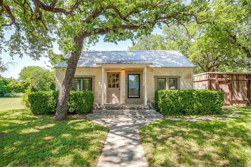 Step into the timeless charm of this beautiful completely updated 1942 home where character, history and modern comfort come together seamlessly.  Nestled on a spacious, tree-dotted lot with wide-open green space, this property offers the peaceful feel of country living right in the middle of town.  Inside, you'll find a fresh, refined interior blending historic charm with modern finishes, including original wood flooring and flagstone, an updated bathroom featuring sleek dual vanities, quartz-style countertops, designer fixtures ad warm natural wood cabinetry. Natural light fills the home, creating an inviting atmosphere that feels both cozy and sophisticated. Outside, the expansive yard provides endless possibilities- from entertaining and gardening to simply enjoying quiet evenings under the Texas sky. Mature trees, open space, and the home's classic stone exterior add to the storybook appeal of this rare property. Whether you're drawn to the history, the updates, or the peaceful setting, this charming 1942 gem offers a unique opportunity to own a home with both soul and style.

Home comes with refrigerator, washer, dryer.  
Carport with 2 spaces. Also has a garage-storage-workshop
