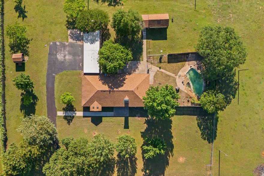 Discover peace and privacy on nearly 4 fully fenced acres behind an electric gate. This beautifully maintained property offers 2,153 sq ft of comfortable living in the main home, featuring 3 spacious bedrooms, with a 15x12 bonus sitting area or office off primary bedroom, 2 updated full baths, and a 2-car garage. Inside, you’ll find stunning granite countertops in the kitchen and baths, wood flooring throughout, tile in all wet areas, fresh paint, and a water filtration system in the kitchen for added convenience. Ideal for entertaining or relaxing, the backyard oasis includes a sparkling pool with spa and water features, surrounded by tranquil views of open space. Separate guest quarters (150 sq ft) provide a private 1 bed-1 bath retreat, perfect for visitors or a home office. Bring your hobbies and animals—this property includes a 240 sq ft shop with electric, a 12x12 stall with power and fenced pen, a water well, a rainwater harvesting system, full gutters, a 3-car carport, and plenty of room to roam. A rare opportunity to enjoy quiet country living with all the modern comforts!