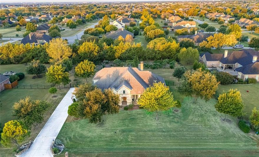 Embrace the rare opportunity to own this Tuscan-style Highland Estate on a full acre in the highly desirable Parker area, served by Allen ISD. Warm, inviting, and exceptionally well maintained, 5403 Englenook Drive is designed for families who seek elevated living without compromise.
Step through double doors into an open, flowing floor plan anchored by hand-scraped hardwood flooring, soaring ceilings, and an abundance of natural light. The main level features two bedrooms—including an elegant primary suite—plus a formal study with French doors and a formal dining room connected to a butler’s pantry for effortless entertaining.
The heart of the home is the gourmet kitchen, featuring granite countertops, custom wood cabinetry, tile backsplash, oversized island, and state-of-the-art appliances, including double ovens, a gas cooktop installed in 2023, and a dishwasher added in 2024. The kitchen opens to a family room highlighted by a striking stone fireplace and built-ins, creating a warm, inclusive atmosphere perfect for family gatherings.
Retreat to the primary suite, where a bay window frames serene garden views. The spa-style en suite bath offers dual vanities, a soaking tub, a separate shower, and a generous walk-in closet. Upstairs, three additional bedrooms each include private en suite baths and walk-in closets, along with a spacious game room and a dedicated media room—ideal zones for kids, guests, or family movie nights.
Outside, enter a covered patio with an extended patio in the back by about 400 sq ft, your private sanctuary of mature trees, flourishing gardens, and a boutique vineyard featuring grapevines, pomegranate, fig, and pear trees, along with herbs and vegetable beds. A trellis-shaded sitting area, stone pathway, and scenic privacy plantings complete this serene retreat. 
Recent upgrades: Roof 2025, Two HVAC systems 2023,  & water heaters 2024. 
Other highlights: Three-car garage with room for freezer and workshop.