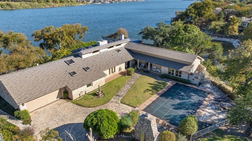 Welcome to an iconic Granbury waterfront retreat, where every day feels like a vacation. This incredible Lake Granbury home offers over 3,900 square feet of well-designed living space with four bedrooms and four bathrooms. The moment you step through the double iron doors, you're greeted by a breathtaking wall of windows showcasing expansive lake views from nearly every room.

Perfect for relaxed living or entertaining, the home showcases two spacious primary suites, an updated chef’s kitchen, and an inviting living area that flows effortlessly outdoors. The extensive patio area is the ideal spot to unwind or host guests, complete with an outdoor fireplace and a refreshing in-ground pool. Whether you're sipping coffee at sunrise or enjoying evening breezes at sunset, the setting simply doesn’t disappoint. Sitting on 1.51 acres at the end of a quiet cul-de-sac, this property promises peace, privacy, and plenty of room to roam. With over 600 feet of prime water frontage, a deep-water boat dock, and space to expand it, lake living has never been easier—or more fun. In additional, this property consists of 4 lots.  With a slight modification of the garage and the tennis court removed, 2 lots could be sold off separately.  65 roof mounted solar panels provide for drastically reduced electric bills! Bonus: You're tucked away just enough for solitude but still perfectly placed close to local attractions and conveniences. So whether you're seeking sanctuary, ready to entertain, or just want to collect a few adventurous fish tales or family boating fun,, this home is ready when you are.