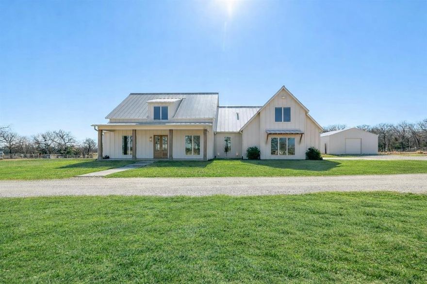 Set on 4± pristine acres (additional ±7AC available) in the heart of horse country, this 2024 modern farmhouse exudes quiet luxury & intentional design. Spanning 3,229SF, the 5 bedroom, 3.5-bath residence pairs clean architectural lines with warm, organic textures. A light-filled open-concept layout is framed by expansive windows that capture gorgeous pasture views & flood the interiors with natural light. Ten-foot ceilings, level 4 smooth wall finishes, & a refined material palette create an atmosphere that feels both sophisticated & effortlessly livable. The kitchen flows seamlessly into the living and dining spaces, designed for elegant entertaining yet perfect for everyday comfort. Thoughtfully constructed for longevity and efficiency, the home features full spray-foam insulation, a trench-and-pier slab with post-tension reinforcement, and a Class IV standing seam metal roof offering architectural distinction and potential insurance savings. The Hardie board-and-batten exterior delivers timeless appeal with minimal maintenance, while oversized glass doors blur the line between indoors & out. Beyond the home, the acreage unfolds with cross-fenced pastures, new top-rail pipe fencing with 5’ no-climb wire, an access-controlled gated entrance, & water lines and spigots to the pastures. A spray-foam insulated 30’x40’ shop, barn, loafing sheds, provide both beauty & function. Ideally positioned just minutes from Whitesboro with convenient access to I-35, approximately one hour to Fort Worth & within reach of DFW International Airport, the property offers the rare balance of rural serenity and metropolitan accessibility. Weekends can be spent boating on Lake Texoma or enjoying the recreation of Lake Ray Roberts—both just a short drive away—while returning home to privacy & refined ranch living. Whether envisioned as a country retreat or working ranchette, this property offers modern ranch living. Additional acreage offers a pond and pastures.