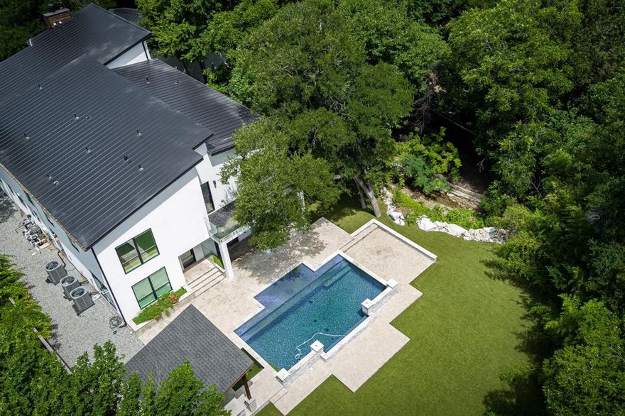 Luxury and comfort blend effortlessly in this exceptional open-concept home at 13032 Copenhill Road, situated in one of Dallas’ most desirable neighborhoods. With 6 spacious bedrooms, multiple living areas, a cozy loft, and a dedicated media room, this expansive residence is thoughtfully designed to accommodate both everyday living and upscale entertaining. Step inside to discover low maintenance flooring and custom light fixtures throughout, adding style and warmth to every space. The heart of the home is the chef-inspired kitchen, featuring stainless steel appliances, a large center island, and seamless flow into the dining and living areas—perfect for gathering with family or hosting guests in style. A wine cellar tucked beneath the stairs adds a unique and elegant touch. Outdoor living is just as impressive. Enjoy your private resort-style backyard complete with a sparkling pool and spa, custom putting green, and a meandering stream that adds serenity to the beautifully landscaped surroundings. Low-maintenance turf in both front and back yards ensures year-round curb appeal, while a tall privacy fence provides peace and seclusion. Multiple balconies and deck areas offer a variety of spots to relax, entertain, or simply enjoy the outdoors. A detached 3-car garage provides ample parking and storage, completing the home’s long list of desirable features. 13032 Copenhill Road is more than just a home—it’s a lifestyle destination. From its flexible layout to its luxurious finishes and thoughtfully designed outdoor spaces, this property offers the perfect blend of timeless elegance and modern convenience. Don’t miss your chance to own this rare Dallas gem.