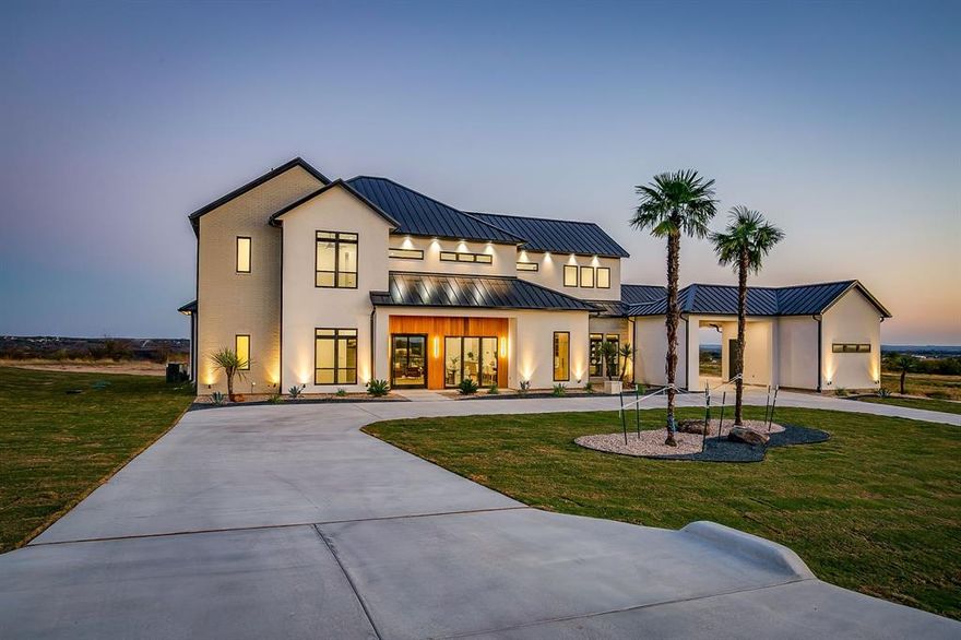 PREPARE TO BE CAPTIVATED! This high class architectural standout is the definition of bold, refined luxury and exceptional sophistication! Nestled in the sought-after Santorini gated community, you will find this one-of-a-kind home ready to dominate the first impression. As you drive through the Porte-Cochere–style design and half circle driveway, you will walk through a striking 6×8 metal and glass pivot door. Instantly welcome by a warm stone accent wall which opens to an airy, open-concept layout where a glass staircase ascends to a loft overlooking the living area. What a spectacular living room here with floor to ceiling Venetian-plastered fireplace and 24 foot ceilings with a full custom bar with additional sink and accent stone wall. The slated design kitchen is equipped with Taj Mahal countertops with a dropped edge finish, top of the line built-in SKS appliances, custom cabinetry including spice rack and utensils drawers, pot filler above gas cooktop, under cabinet lighting and an unbelievable pantry with custom wine bar. The dreamy primary suite offers an unbelievable cascading waterfall shower in what feels like a five-star resort style spa with 12 foot seamless glass walls. Each bedroom offers its own ensuite bath and impressively spacious closets, while the upper level features a flexible living space and a game room equipped with its own bar—perfect for entertaining. Home office with built-in's and laundry room with dog wash.  Enjoy beautiful wide-open views off the back patio with a glass of wine and cozy up to the wood-burning fireplace. This truly is a stunning design, packed with every luxury feature and is ready for YOU to call this place home for good!