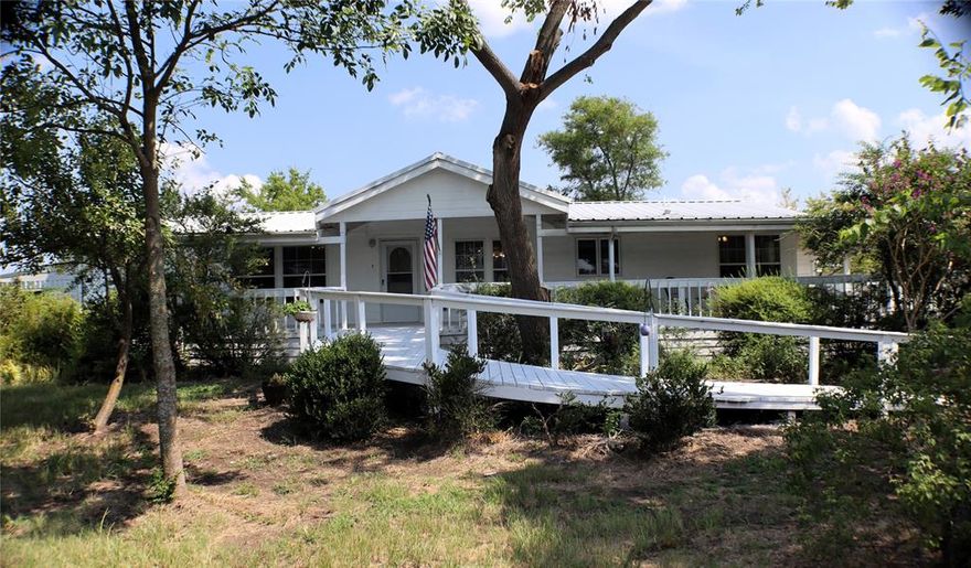 Welcome to your new paradise! This property is perfectly set up for your animals, featuring a 120' x 70' Covered Arena, 100' x 60' barn with 12 x 40 office concrete pad, 12 x 10 wash bay with hot and cold water, 12 x 12 stall, interior panel pen, permanent hitching post and cross tie posts. There are two fenced paddocks, a large loafing shed with shelter on two sides, and a pond stocked with Channel Catfish. The middle pasture is mowed for riding and dressage, while the back pasture is spacious enough for a regulation-sized driving arena. This Oak Creek Modular home includes 3 bedrooms, 2 baths, a dining, living room, and additional family room. Enjoy the covered and screened back porch, covered connecting the porch to the two-car garage, and an extra carport for parking. Additional features include a greenhouse area, a chicken coop, a tool shed, and a covered front porch spanning the length of the house. The home is surrounded by cyclone fencing and adorned with a variety of plants, perfect for the gardening enthusiasts—featuring Carefree Beauty, Knock Out, Cascade, and Mermaid Roses, Crape Myrtles, Pear, Peach, Elm and Red Oak Trees, Trumpet Vines, Purple Irises, Garlic, and Asparagus, and so much more. This is a must-see property to truly appreciate all it has to offer!