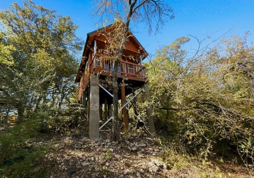 One-of-a-Kind Minimalist Living! Tiny Tree House Retreat. Experience the charm of tiny house living with this truly unique, minimalist tree house tucked away at the end of a cul-de-sac. Offering that secluded feel and panoramic views from every window. Step inside to discover two full-size loft sleeping areas, one accessed via a ladder and the other by a rock climbing wall- full of character, adding that fun, adventurous touch to your everyday routine. The thoughtfully designed bathroom features floor-to-ceiling tile, dual drains, a commode, and pedestal sink-all in one easy to clean space. Relax on the covered front and back porches while taking in serene greenbelt views in every direction. Enjoy the perks of low utility costs, no water bill, a fenced yard, and a 1-car carport. A truly rare find- perfect for those who value simplicity, privacy, connection to nature, and a one-of-a-kind living experience. Now thats the perfect hideaway, right?Experience life, simplified.