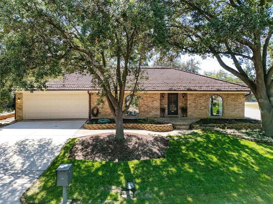 Nestled on a quiet, grand corner lot in the established Wedgwood neighborhood, this move-in-ready ranch is surrounded by mature trees and spacious lots. No cast-iron drain worries here – they’ve already been fully replaced! Fresh carpeting graces all bedrooms, while new luxury vinyl plank flows throughout the living areas. The popular split-bedroom layout offers privacy, with an oversized primary suite that easily accommodates a sitting area, small office, or nursery. You’ll love the expansive dual-sink vanity, double walk-in closets, and abundant built-ins and storage found in nearly every room – including a dining room closet! Two generous living areas, formal dining, and a bright eat-in kitchen provide ultimate flexibility for entertaining, remote work, or simply spreading out. Step outside to a covered patio and fully fenced backyard – perfect for pets, play, or summer gatherings. Hobbyists and DIYers will appreciate the large detached storage workshop. Crowning this home is a premium Gerard Category 4-rated metal roof (beautiful tile-look, expertly installed by Joe Hall Roofing) with a stash of spare tiles conveniently stored behind the shed for any future needs.
Additional peace of mind: transferable lifetime foundation warranty with NO transfer fee, plus quick access to the Chisholm Trail. Fresh, clean, functional and ready for your personal touch – come see why this Wedgwood classic feels like home the moment you walk in.