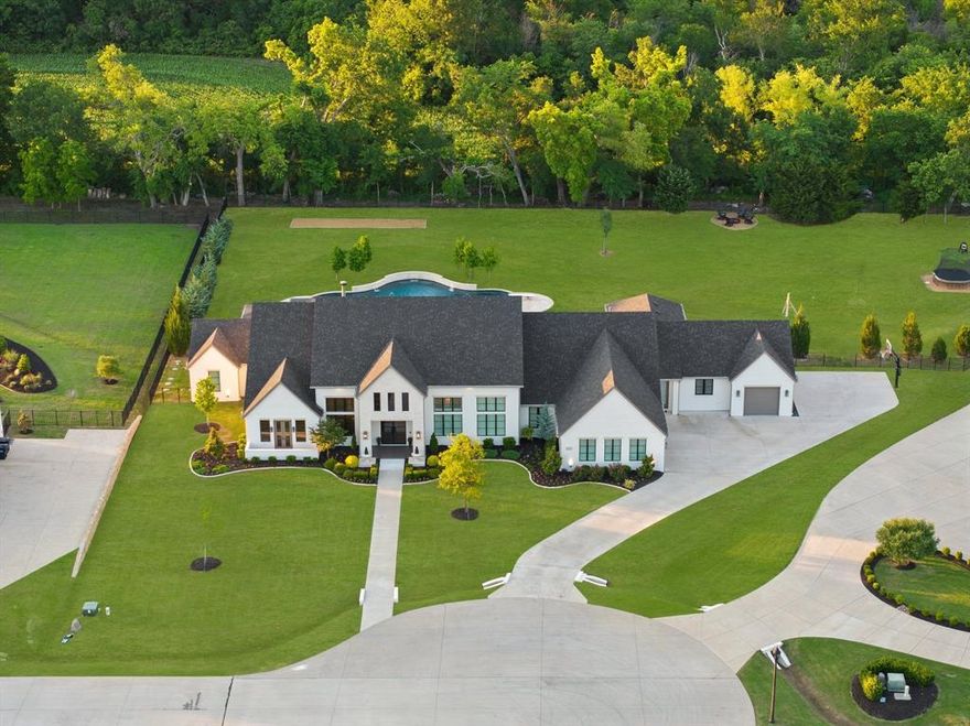 Beautifully anchored at the end of a tranquil cul-de-sac in a prestigious gated enclave, this residence has been meticulously crafted into a true retreat, featuring premium upgrades, luxurious finishes, and an open-concept layout. Upon arrival, the impeccable landscaping, custom lighting, and extended driveway set the tone. Step inside, and you’re met with gleaming hardwood floors and designer light fixtures that elevate every room. Among the standout features are a wood-paneled office with built-in shelving and a wine room, catering to both work and leisure. A second office offers flexibility-ideal for a dual work-from-home setup, a study space, or studio. Equipped with premium appliances, the kitchen boasts double islands for added prep and gathering space, Sub-Zero refrigerator, a Miele coffee system, and a Hoshizaki ice machine. Plantation shutters adorn the windows and the Control4 system integrates technology with convenience. The primary suite is a sanctuary, featuring a spa-inspired bathroom with a steam shower, soaking tub, dual vanities, built-in coffee bar, custom closet system, private gym, and exclusive access to the serene back patio. Designed with everyday living in mind, the laundry room offers custom cabinetry, a dog shower, and a pet feeding station. For peace of mind, a safe room enhances security, while a Texas basement provides the opportunity to add finished square footage. For relaxation and entertainment, the home offers unparalleled amenities. The theater, complete with a wet bar and ice machine, is ideal for movie nights, while the game room is designed with wiring for dual gaming systems. Step outside into an entertainer’s paradise, where an 80,000-gallon pool with water features, heated spa, and a diving board anchors the backyard. Motorized shades, patio heaters, and a fire pit area promise comfort year-round, while features like a treehouse with a zip line and trampoline deliver endless fun. Experience the pinnacle of upscale living.