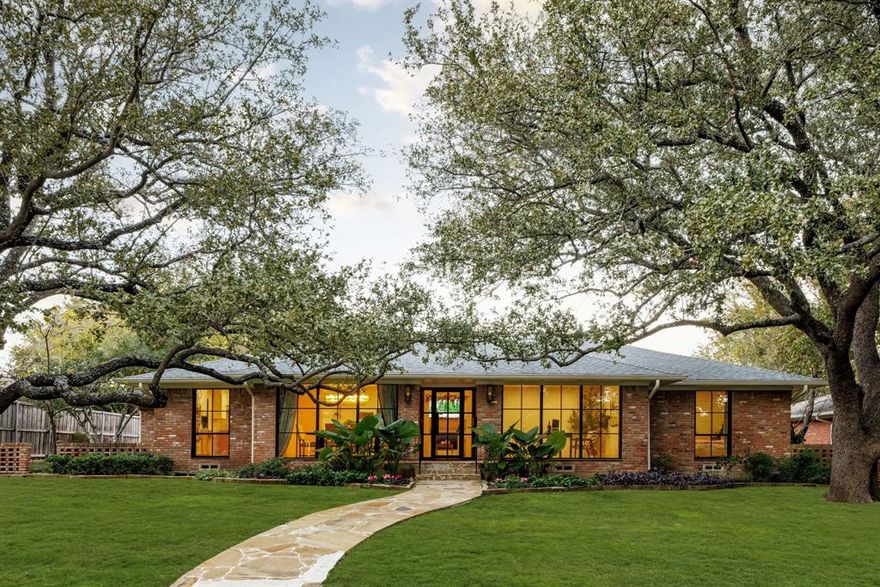 Positioned on a picturesque .28-acre lot in the heart of Preston Hollow, this architecturally striking residence delivers a level of character, craftsmanship, and finish rarely found at this scale. Mature live oaks frame the approach, while natural brick, floor-to-ceiling windows, gas lanterns, and a steel front door create a timeless, elevated presence. Inside, a refined yet comfortable aesthetic unfolds with a warm palette of curated materials, anchored by wide-plank oak flooring throughout. The entry is thoughtfully balanced by a formal dining room and a private study behind French doors. At the center of the home, the chef’s kitchen serves as both a visual focal point and gathering space—anchored by a spacious island and appointed with custom cabinetry, Taj Mahal quartzite, handmade zellige tile, and an integrated Miele and Thermador appliance package, including dual dishwashers. A separate bar enhances the entertaining experience, while the kitchen flows seamlessly into the primary living, dining, and lounge areas. The living room offers 10-foot ceilings, a beautifully scaled fireplace, and custom built-ins, opening effortlessly to a secondary den or playroom. Bifold doors create a dramatic 12-foot opening, extending the living experience to the patio and expansive backyard. The primary suite is a true retreat with backyard access, custom millwork, and a spa-inspired bath featuring dual vanities, elevated finishes, a soaking tub, and a generous walk-in closet. Well-appointed secondary bedrooms offer excellent storage and share a thoughtfully designed bath. Additional highlights include a statement powder bath with floating vanity, mudroom with built-in lockers, and a large two-car garage secured by an electric privacy gate. Outdoors, the deep backyard is framed by mature landscaping and manicured grounds—offering a private retreat with plenty of play space. A rare opportunity to find this quality at this scale + walking distance to Preston Hollow Village.