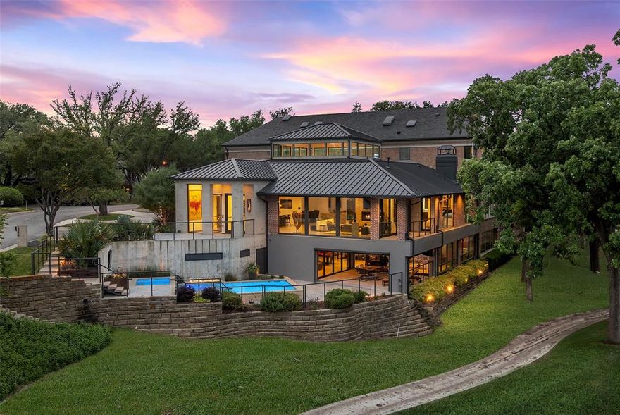 17214 Club Hill is a refined expression of modern luxury, thoughtfully reimagined and expanded in 2020 to nearly 8,964 square feet. Taken to the studs, the residence was rebuilt with all new systems—electrical, plumbing, HVAC, insulation, windows, and roof—and enhanced by integrated Control4 technology for seamless whole-home audio, video, lighting, and security. The interiors are expansive yet composed, defined by floor-to-ceiling Pella architectural windows and multi-slide doors that frame sweeping views across two fairways and White Rock Creek. Level 5 wall finishes, porcelain concrete flooring, custom wood ceiling panels, and stone feature walls create a layered architectural backdrop, while dual floating staircases with integrated lighting serve as sculptural focal points. Linear fireplaces, motorized Lutron shades, and curated lighting further elevate the atmosphere. The kitchen is both functional and beautifully appointed, featuring a large center island, Thermador appliance suite with gas range, double ovens, warming drawer, and dual dishwashers, along with a butler’s pantry and secondary refrigeration. Additional spaces include a wine and whiskey room, media room with 120” screen, game and billiards room, private office, guest suite, and generous laundry and storage. Outdoor living is intentionally layered, with a multilevel pool and spa, firepit, and terraced landscaping positioned to capture the home’s elevated vantage point. Motorized screens create seamless indoor-outdoor transitions, while a circular drive, detached three-car garage, and HOA-maintained grounds offer a true lock-and-leave lifestyle. Bent Tree is entering a new chapter with a 65,000-square-foot clubhouse and a course transformation by Beau Welling. Long recognized as a premier golf destination, the Desmond Muirhead-designed course is being thoughtfully reimagined, complemented by exceptional racquet facilities and a culture of excellence.