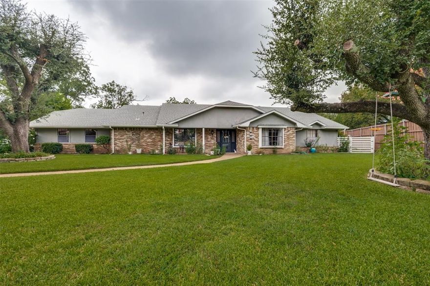 This stunning four-bedroom, three-bath retreat nestles in a peaceful, well-established neighborhood. Step inside and let a sparkling chandelier welcome you into the elegant foyer. The home boasts two generous living areas, where a dramatic rock fireplace, soaring vaulted ceilings, and eye-catching lighting set the stage for memorable moments. Just off one living space, a formal dining room dazzles with a chic light fixture and a bold brick accent wall. The island kitchen is a chef’s dream, featuring a gas cooktop, double oven, and abundant storage for all your culinary adventures. Sunlight pours into the breakfast nook, creating a cheerful spot to savor your morning coffee. Throughout, fresh paint and gleaming porcelain tile infuse the home with modern style, while new door hardware adds a touch of sophistication. The primary bedroom is a private sanctuary, complete with its own chandelier and an ensuite bathroom with a separate shower and dual vanities. Three additional bedrooms and two bathrooms ensure comfort and space for everyone. Unwind in the sunroom, where decorative lighting and serene backyard views invite relaxation. The expansive covered patio is perfect for lively outdoor gatherings, opening to a lush backyard that connects to a scenic walking path. For added convenience, a two-car garage awaits, and the home’s prime location puts everything within easy reach.