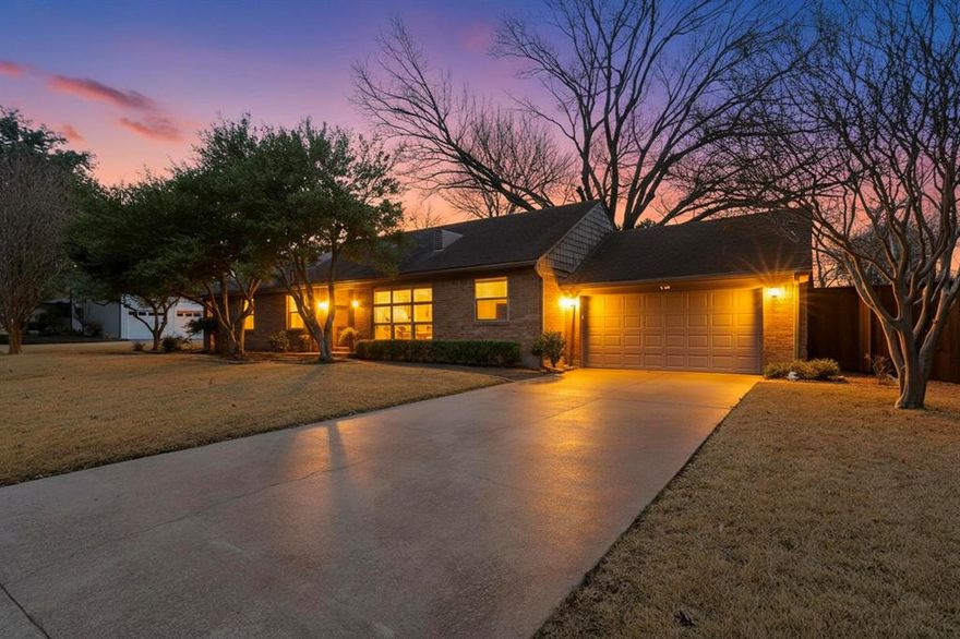 Tucked away on coveted Emerald Isle, a hidden enclave along White Rock Lake known for its mature trees and classic 1950s character, this beautifully expanded residence offers a rare blend of timeless charm and thoughtful modern living. Set on a landscaped .30-acre lot, the home provides a peaceful, private setting just a short walk from the lake at the end of the street. A recent addition has enhanced both space and functionality, now offering four bedrooms, three baths, a dedicated office and two light-filled living areas designed to connect seamlessly with the outdoors. A wall of windows frames views of the expansive backyard, bringing natural light and a sense of calm into the heart of the home. The design-forward eat-in kitchen features granite countertops, abundant white cabinetry and a built-in appliance garage for concealed microwave and pantry storage. A custom banquette beneath picture windows creates an inviting dining space, anchored by a distinctive custom light fixture that adds architectural interest. The private office is enclosed with glass doors and overlooks the backyard, creating an inspiring work-from-home environment. The newly added primary suite offers a refined retreat with dual vanities, an oversized glass-enclosed shower and a generous walk-in closet. The utility room is thoughtfully designed with extensive storage, a sink and convenient access to a fenced dog run through a dedicated doggie door. Additional features include a Generac generator for peace of mind during Texas storms and mature landscaping that enhances privacy and curb appeal. Quiet, established and moments from White Rock Lake, Emerald Isle offers a truly special lifestyle — and this home delivers it with style, space and intention.