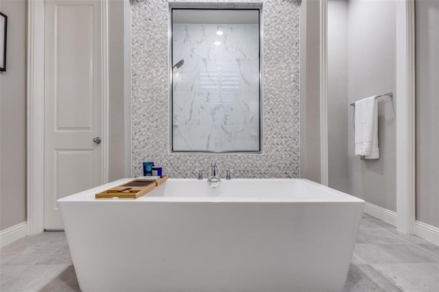 ****PRICE IMPROVEMENT**** Stunning Highland home in Trinity Falls offering 4 bedrooms, 5 bathrooms, and a 3-car tandem garage with EV charging. This light-filled, open-concept design features white oak flooring, vaulted wood-beamed ceilings, a floor-to-ceiling fireplace, and a dramatic two-story wall of windows with sliding glass doors. The chef’s kitchen includes white cabinetry, quartz countertops, an oversized island, and seamless flow into the dining and living areas—ideal for everyday living and entertaining. Sliding doors extend the living space to a covered patio with gas line for a future outdoor kitchen or firepit, plus landscaped grounds with raised garden beds. The primary suite is a private retreat with a spa-style bathroom featuring a freestanding soaking tub, walk-in shower, dual vanities, and marble finishes. The first floor also offers a dedicated home office, secondary en-suite bedroom, mud bench, and utility room with sink and cabinetry. Upstairs includes two additional bedrooms, a spacious game room, and a separate media room with dry bar—perfect for movie nights or hosting guests. Additional upgrades include tray and vaulted ceilings, mostly 8-foot interior doors, Ring doorbell and camera, transferable Starlink internet, sealed driveway, and custom walkway. Conveniently located near Frazier Elementary and the Trinity Falls amenity center, this home combines thoughtful design, modern upgrades, and access to resort-style community features.