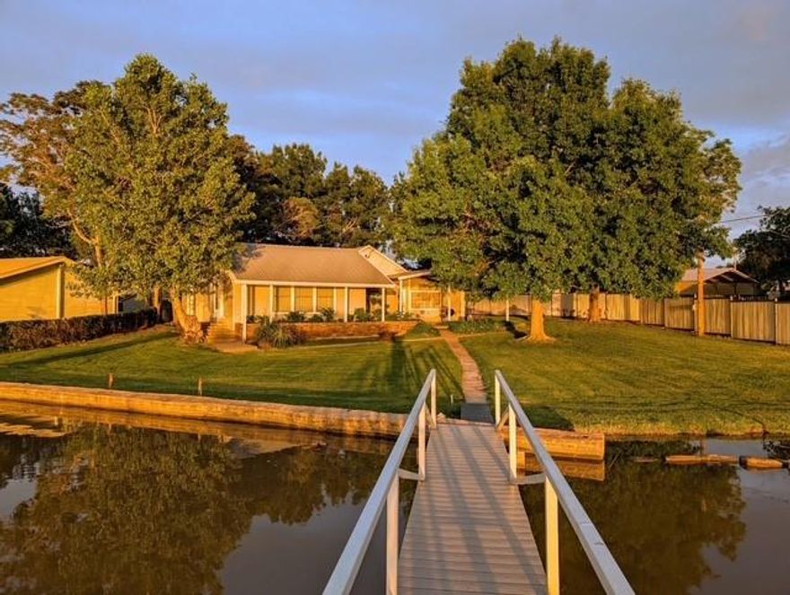 Prime Lakefront Opportunity! This older 3-bed, 2-bath cabin sits on a prime, level lakefront lot in a protected no-wake cove with 20’+ deep water at the dock—ideal conditions for a high-end custom build or luxury vacation retreat. The existing cozy cabin offers large windows with lake views, an open kitchen-living area, a finished room just off the kitchen serves as convenient storage, and a covered porch facing the water, but the real value lies in the incredible lakefront lot: level spacious yard with seawall and easy level walk out to a nice covered deep water boat dock, mature trees, and sunset views that set the stage for a spectacular new build. With steel siding, low-maintenance roof, and comes furnished with short-term rental potential, you can generate income now while planning your future dream project. Lakefronts in popular areas with all these desirable characteristics like this are hard to find—redevelop now or hold for long-term value.