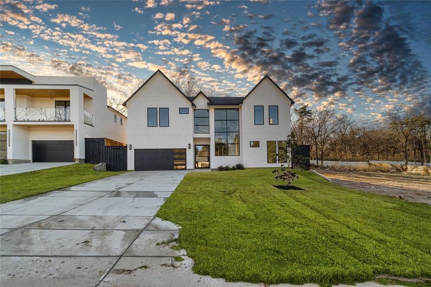 Show-stopping modern new construction with bold architecture and a breathtaking wall of windows that floods the home with natural light. Thoughtfully designed open layout connects the living space to a chef-style kitchen with oversized island, custom cabinetry, quartz surfaces, and statement lighting. Main level includes a private guest suite or home office. Upstairs opens to a dramatic overlook of the living area and a built-in bar with custom shelving, creating the perfect entertaining zone. The primary suite delivers a true retreat with a spa-inspired bath featuring a freestanding soaking tub, oversized walk-in shower, and striking tile work. Designer finishes throughout, wide-plank flooring, modern doors, black hardware, recessed lighting, and ceiling fans in every bedroom. Striking curb appeal with architectural lighting and a clean contemporary exterior. Move-in ready and built to impress.