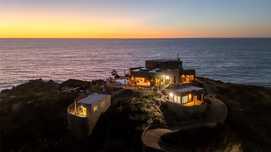 Perched high above the surf breaks of South Cerritos Beach on 2.5 acres of dramatic oceanfront, Arriba de la Roca delivers a view that stops time. From this elevated vantage, the Pacific unfolds endlessly below—waves peeling along the point, sky and sea merging into a cinematic horizon. Private, powerful, and impossible to duplicate, this property stands alone.
Originally conceived as a boutique hotel and now reimagined as a striking six-bedroom oceanfront compound, Arriba de la Roca offers both presence and purpose. It functions seamlessly as a legacy family estate, an ultra-luxury short-term rental, or an exceptional venue for destination weddings and private events—combining privacy, scale, and income potential.
The main residence is designed to frame the setting. An open living, dining, and kitchen space flows toward the ocean through expansive sliding glass doors, inviting coastal breezes and uninterrupted views. A hammered copper fireplace and bar anchor the space, while a live-edge island and custom cabinetry add warmth—always deferring to the view as the star.
Outdoor living defines the experience: a horizon-facing pool, Pacific-view jacuzzi, fire-pit lounge, and open-air cantina bar create unforgettable sunset gatherings.
Four private guest casitas are positioned throughout the landscape, each with its own terrace and sweeping ocean views. The two-story primary suite stands alone with commanding surf outlooks, a copper soaking tub, custom finishes, in-suite laundry, and secure storage.
Below, a separate two-bedroom caretaker’s home, three-bay garage, and standalone workshop with bath provide exceptional functionality. Fully off-grid, the estate features upgraded solar with battery storage, new propane backup generator, four 10,000-liter cisterns, storm shutters, and golf carts. Originally completed in 2012 and extensively renovated over the past three years, Arriba de la Roca has been meticulously maintained.
There is simply nothing else like it.