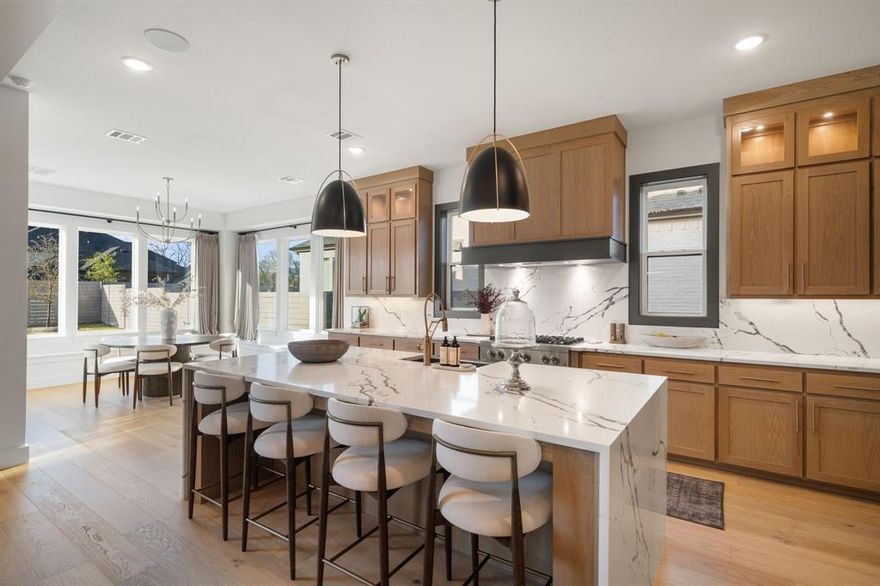 Welcome to this beautifully designed home in one of McKinney’s most sought-after communities, where elevated finishes and thoughtful design come together seamlessly. The main living area makes a lasting impression with soaring vaulted ceilings, exposed wood beams, a striking fireplace feature wall, and expansive sliding doors that create a seamless indoor-outdoor connection to the covered patio. The kitchen is both functional and refined, featuring a waterfall island, full-height cabinetry, designer lighting, and a premium appliance package, all opening effortlessly to the living and dining areas filled with natural light. A designated office with custom built-ins offers a polished work-from-home space, while a private media room provides the perfect setting for entertaining. The primary suite is privately positioned and showcases vaulted ceilings, abundant natural light, and a spa-inspired bath complete with a freestanding soaking tub, oversized walk-in shower, dual vanities, and extensive cabinetry. Upstairs, additional living space with an open-to-below design enhances the home’s airy feel and provides added flexibility. Additional highlights include a wet bar, wide-plank wood flooring, curated designer finishes throughout, and a layout designed for both everyday living and entertaining. Situated on a well-sized lot with a covered outdoor living area, this home offers a refined blend of modern style and comfort, all within close proximity to top-rated McKinney ISD schools, dining, shopping, and major commuting routes.