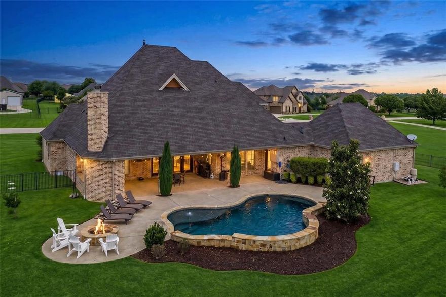 *1 ACRE ESTATE!!*RESORT-STYLE POOL & OUTDOOR LIVING!!*5 BEDROOMS + OFFICE + MEDIA ROOM!!*3-CAR OVERSIZED GARAGE!!*
Introducing this exquisite 5-bedroom, 4.5-bath custom estate, privately situated on a sprawling 1-acre lot in the prestigious Willow Springs Ranch. Surrounded by lush, manicured landscaping, a gated drive through a Porte-cochère welcomes you to a 3-car oversized garage.  The grand interior showcases soaring ceilings and abundant natural light within an open-concept layout. The living room features custom built-ins and elegant French doors opening to the backyard patio, seamlessly blending indoor and outdoor living. The chef’s kitchen is a standout with double islands, dual sinks, a 5-burner gas cooktop, vented exhaust fan, and an oversized walk-in butler’s pantry, plus a beverage fridge and wine rack, breakfast bar seating, and abundant cabinetry—all flowing into the dining and living areas.

The private primary suite offers a refined retreat with serene backyard views and elegant French doors providing direct access to the patio. The spa-inspired ensuite includes dual vanities, a soaking jetted tub, separate shower, and an oversized walk-in closet. Secondary bedrooms are generously sized, with walk-in closets, with two extra bedrooms on the main level as well as a large private office with built-ins. The upstairs bedrooms feature private ensuite baths. Upstairs includes a game room and dedicated media room.

Step outside to a private, resort-style backyard retreat featuring a sparkling pool, fire pit seating, and an expansive covered patio with outdoor kitchen—designed for elevated entertaining and everyday luxury. The sprawling, oversized yard offers exceptional space and privacy, complete with a charming playhouse with electricity and ample room for pets, play, or hosting. Experience private, estate-style living in the heart of Haslet.