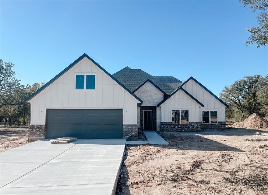 Builder offering interest rates as low as 5.125%—an incredible chance to lock in country luxury at a lower rate! Welcome to Garner Ranch in Brock ISD — where modern design meets country serenity. Set on a beautifully treed 1-acre lot, this brand-new 2,100 sq ft home offers the perfect blend of open-concept living and refined craftsmanship. Inside, soaring vaulted ceilings with striking box beams draw your eye upward, while the seamless flow between the living, dining, and kitchen spaces makes entertaining effortless. Enjoy Luxury Vinyl Plank floors throughout whole home with beautiful tile in bathrooms. The kitchen is a true showpiece, featuring a large island with quartz countertops, stainless steel appliances, and custom shaker-style cabinetry — with a rich stained knotty alder island and lowers complemented by beautifully painted uppers for contrast and warmth. A walk-in pantry and abundant storage complete the space. The spacious dining area overlooks the private backyard, where a covered patio provides the ideal spot for morning coffee or evening gatherings beneath the trees. The split-bedroom layout includes four large bedrooms, including a stunning primary suite with a tray ceiling accented by horizontal box beams and peaceful backyard views. The spa-inspired ensuite offers a soaking tub, dual sinks with quartz counters, elegant tilework, and a massive walk-in closet. Landscaping will include a full sprinkler system, lush sod, and thoughtfully selected plants to enhance the home’s welcoming curb appeal. Additional highlights include a large mudroom, full laundry room, powder bath, and a 2-car garage. Estimated completion: December 2025 — ready for its first proud owner to make it home. Crafted with care and character, this Garner Ranch gem captures the essence of upscale rural living—set on a stunning, tree-filled one-acre lot where quality construction meets everyday comfort.