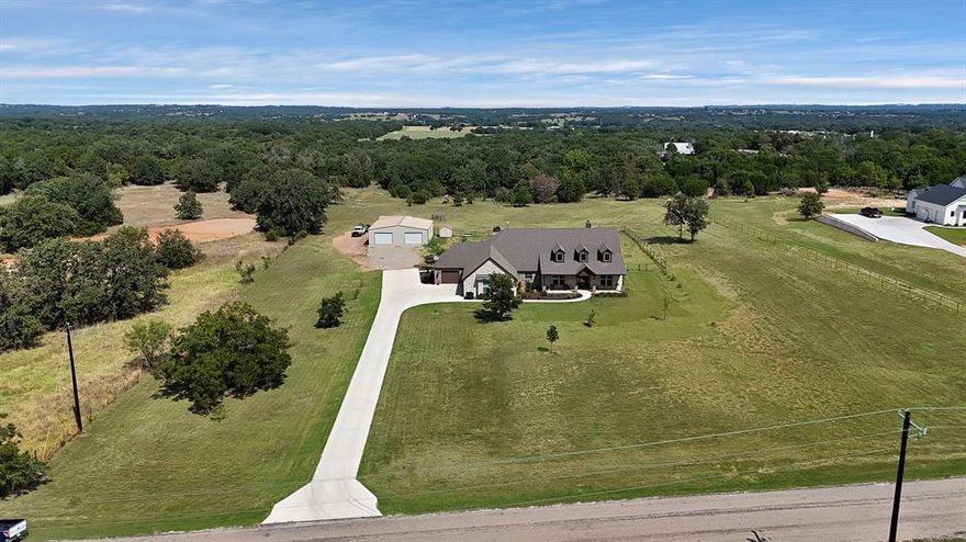 Welcome to your dream retreat in Parker County—an exceptional 3BR, 2.5BA home set on 5.02 lush acres in Peaster ISD. Built in 2022, this like-new residence blends modern luxury with the tranquility of country living and plenty of space. A spacious covered porch with wood columns and an elegant oversized glass-pane front door provides the ideal welcome. Inside, rich dark-stained concrete floors create a warm, sophisticated ambiance that flows throughout. The heart of the home is the gourmet kitchen, showcasing granite countertops, custom dark wood cabinetry, and an oversized eat-in island—perfect for both daily living and entertaining--and with a generously sized walk-in pantry that ensures ample storage. The family room flows seamlessly off the kitchen, where a fireplace is framed by custom built-ins, adding charm and functionality. From the wood beams adorning the high ceilings to the view of the ample tree line through expansive back windows, the details make this open concept area ideal for entertaining. Privacy is enhanced by the split-bedroom floor plan, with the primary suite offering a peaceful escape. The spa-inspired en suite bath features a huge walk-in shower, separate soaking tub, and an expansive walk-in closet designed for maximum organization.Additional features include oversized doors, plantation shutters, walk-in closets in all bedrooms & flexible space for an office or dining room. The spacious laundry room has tons of storage w granite counters and sink. Additional built-in hall shoe storage off the garage adds to the home’s thoughtful functionality, and you will be in awe of the huge garage layout w so much more storage.Outdoor living is just as impressive, w three separate patios ideal for enjoying peaceful mornings or sunset views where you can enjoy deer watching. A large workshop with cross-breeze ventilation from 3 bay doors provides versatile space for hobbies or storage.It is rare to find 5 acres at this price in Parker County, don't wait!